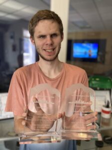 Evan holding up two clear awards