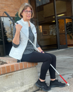 Woman sitting outside, holding a cane